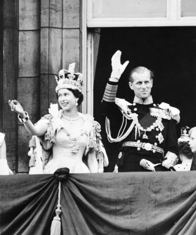 Queen Elizabeth II, wearing the Imperial State Crown, and the Duke of Edinburgh in uniform of Admiral of the Fleet wave from the balcony to the onlooking crowds around the gates of Buckingham Palace after the Coronation on June 2, 1953.  
