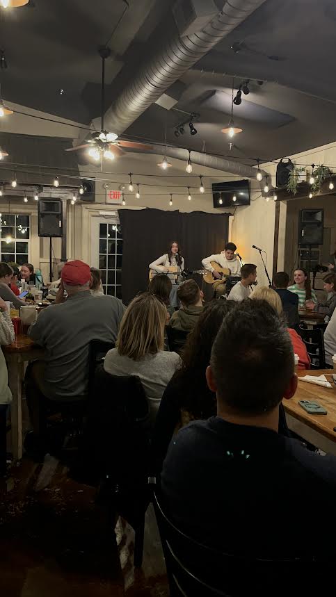 Local singers perform at the Front Porch Cafe in April of 2025 as the crowd eagerly listens and waits for the next song. Spacious seating and a relaxed atmosphere are rustic and welcoming.
